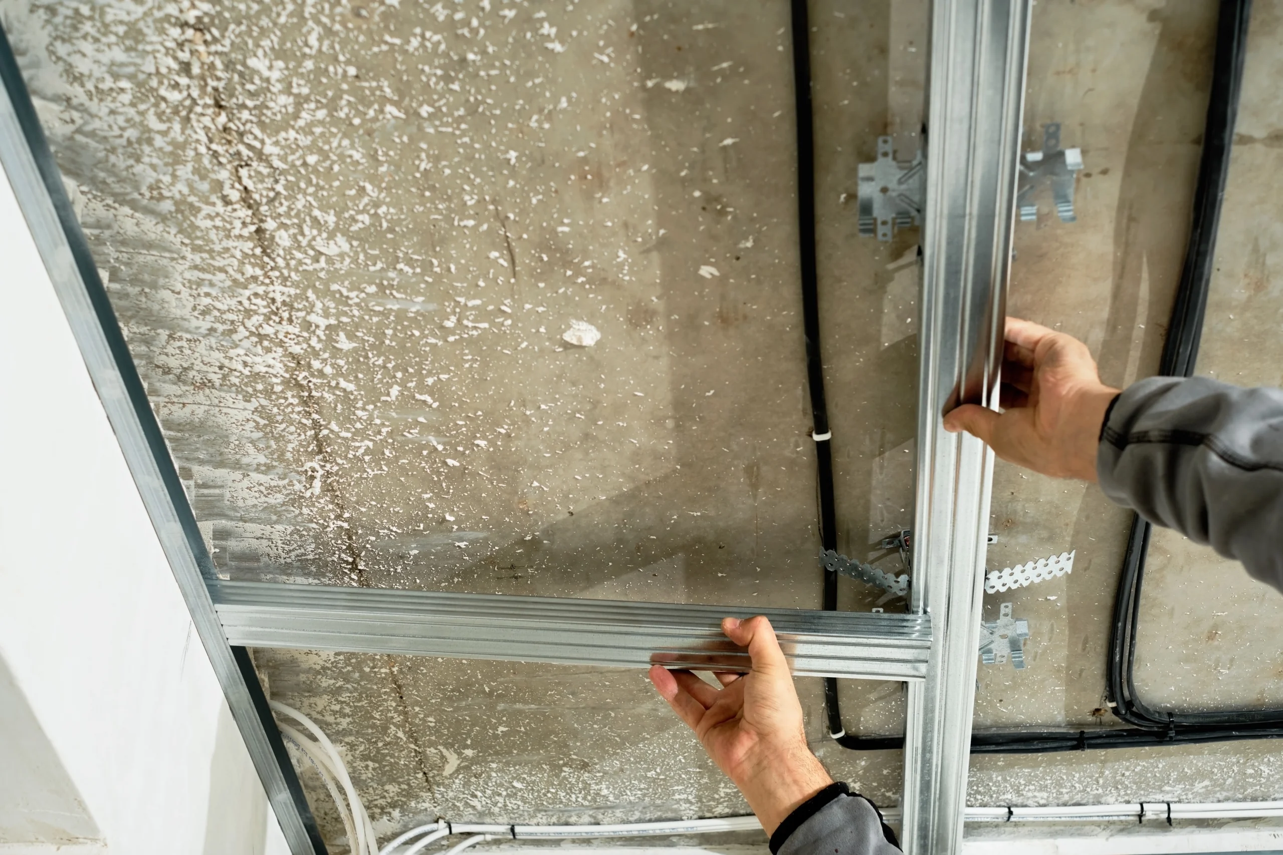 worker-adjusts-metal-profile-mounting-plasterboard-ceiling-frame-close-up-selective-focus-hands-specialist-industrial-renovation-renovation